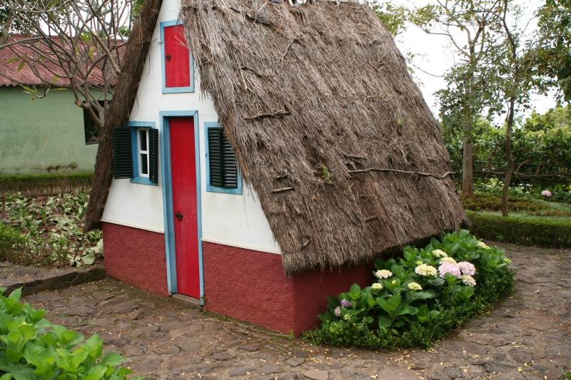 Petite maison à porte rouge dans un environnement verdoyant