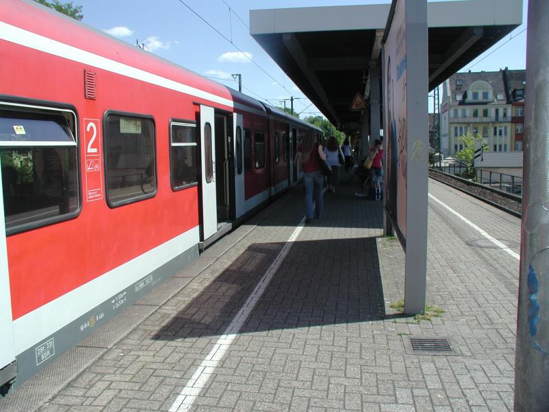 Train régional rouge dans une gare avec des voyageurs