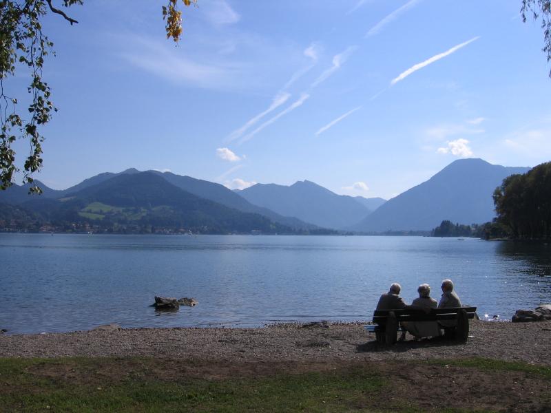 Trois personnes assises au bord du lac devant un paysage montagneux