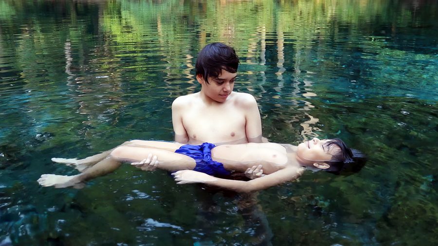 Zwei Menschen schwimmen in einem ruhigen, von dichter Vegetation umgebenen Fluss in Las Estacas bei Tlaltizapán.