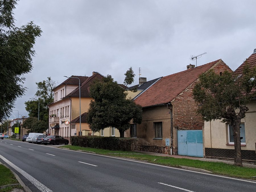 Rue Masarykova à Rudná avec des immeubles d’habitation et une auberge