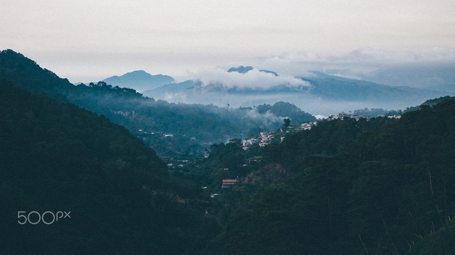 Vue sur La Trinidad avec des maisons et des pentes verdoyantes en Asie du Sud-Est.