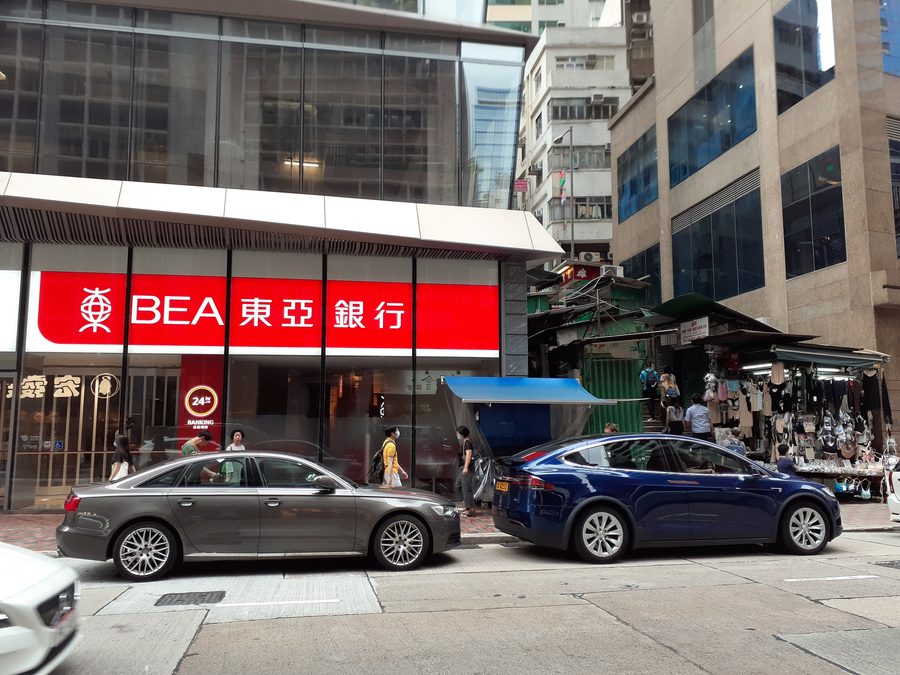 Scène de rue sur Queen's Road Central à Hong Kong avec une succursale de la Bank of East Asia.