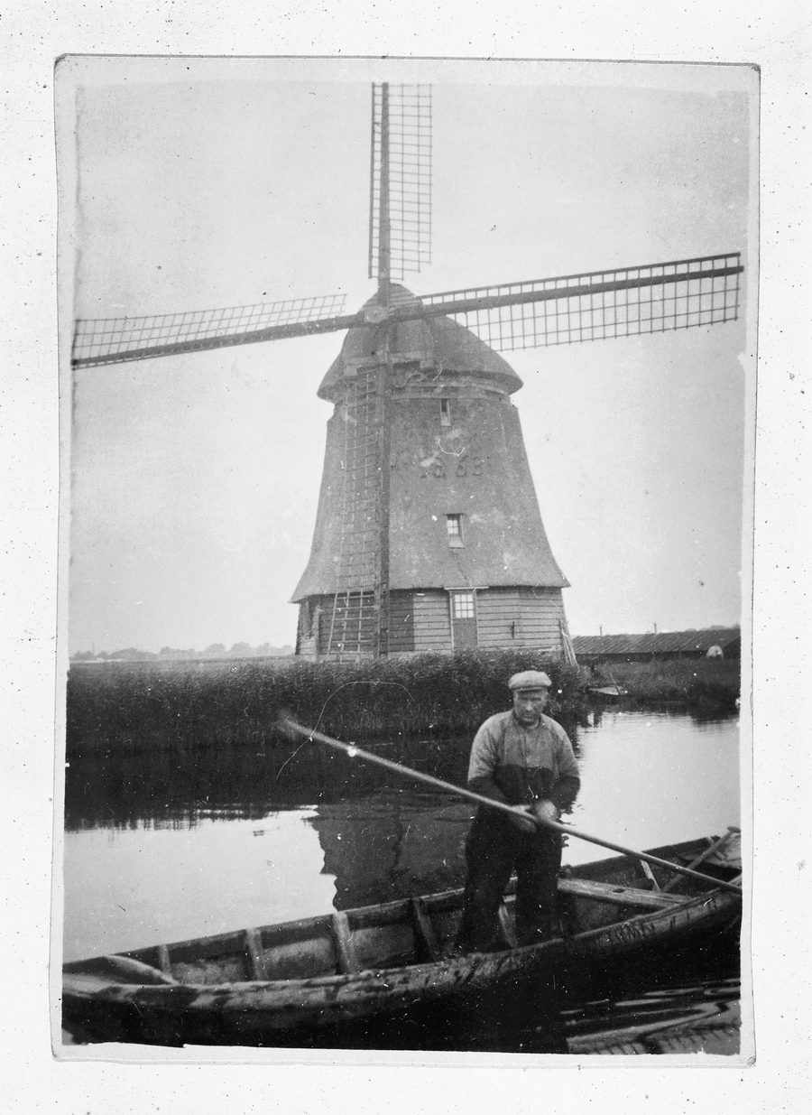 Un homme dans une barque devant le moulin D du polder Geestmerambacht près de Broek op Langedijk