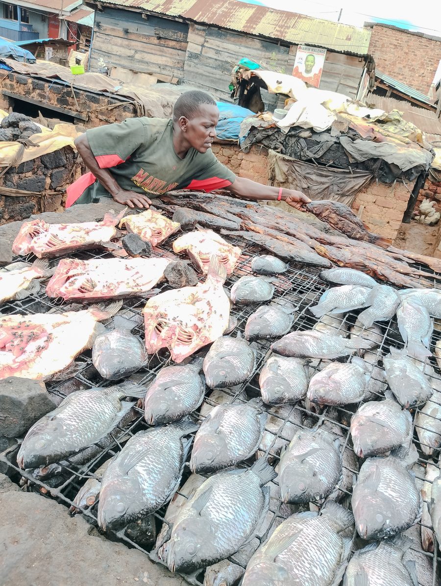 Vendeuse de poisson avec du poisson traditionnellement fumé et frais au Ggaba Landing Site en Ouganda