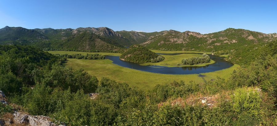 Courbe marquée de la rivière Crnojević entre des versants karstiques verdoyants