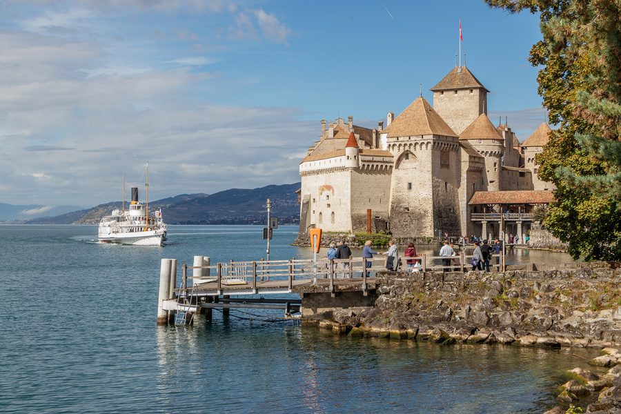 Le château de Chillon au bord du lac Léman, tandis qu’un bateau à vapeur historique approche.