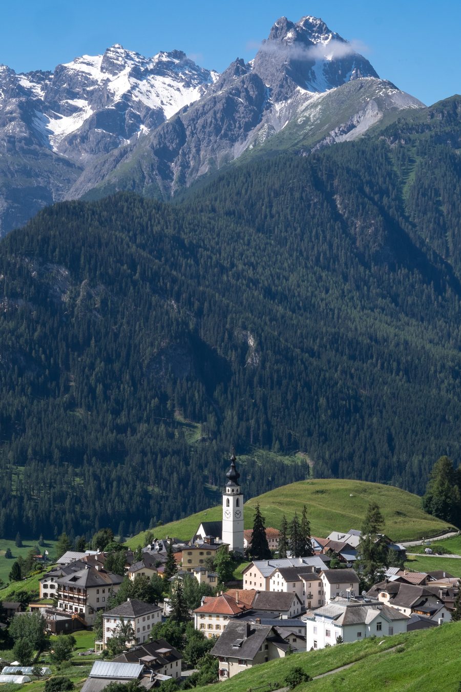 Ftan avec des maisons du village, l’église et un panorama de montagne dans l’Engadine inférieure